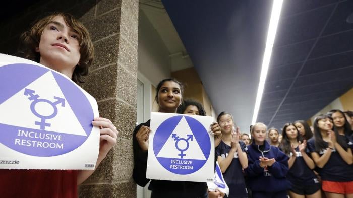 Students hold stickers about to be placed on a new all-gender bathroom as members of the cheer squad applaud at Nathan Hale High School in Seattle, WA on May 17, 2016. 