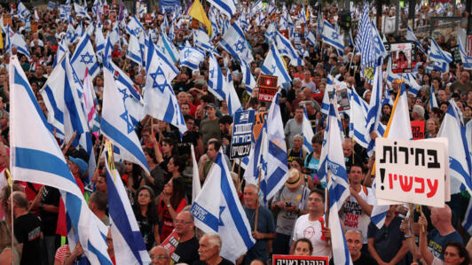 Des militants israéliens brandissent des pancartes et des drapeaux nationaux lors d'une manifestation anti-gouvernementale à Tel Aviv le 29 juin 2024.
