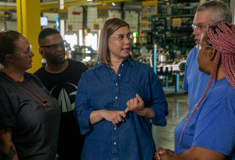 Campaign photo for US Representative Elissa Slotkin. She stands in a factory, wearing goggles, talking with several workers.