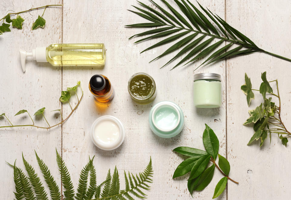 composition of containers with cosmetics and green leaves