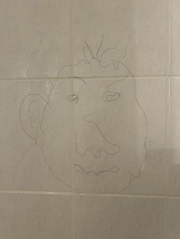 A simple line drawing of a face on tiled wall