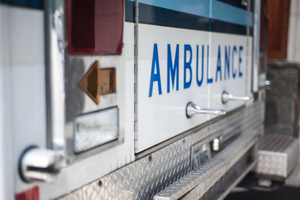 Close-up of an ambulance with visible rear-facing panels and the word "AMBULANCE" on its side
