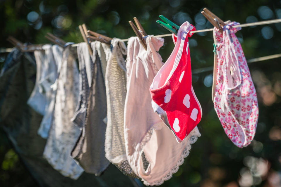 Undergarments of various styles and patterns, including a red one with hearts, hanging on a clothesline outdoors