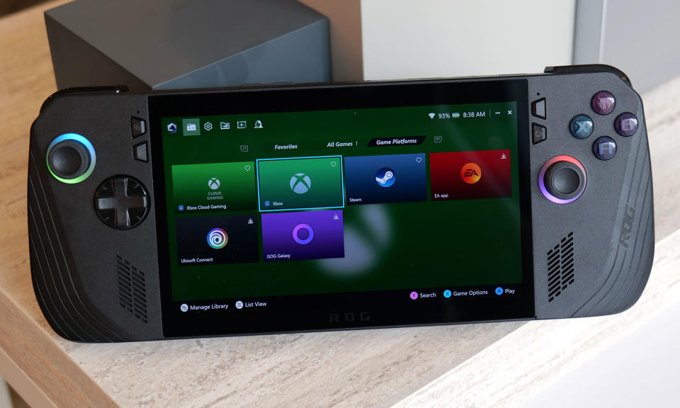 The ASUS ROG Ally X gaming handheld leaning against some cubic ornaments. ON its screen is a selection of providers like Xbox Game Pass and Steam.