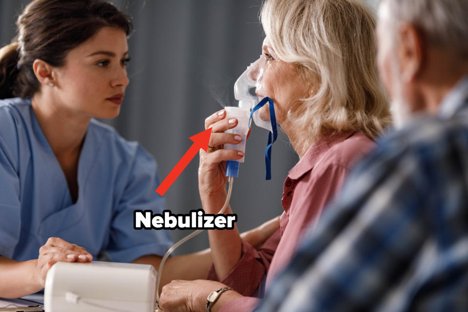 A healthcare worker assists an elderly woman using a nebulizer while an elderly man looks on