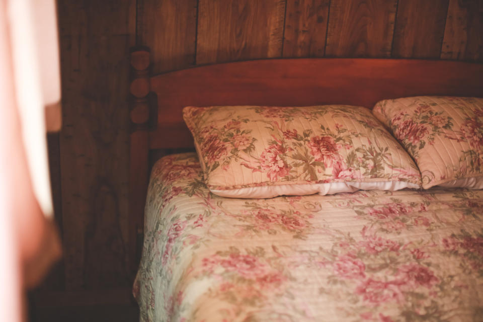 A cozy wooden bedroom with a bed featuring a floral-patterned quilt and matching pillows