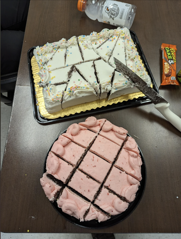 Two cakes, one with white icing and sprinkles and the other with pink icing, both pre-sliced into pieces. There is a Reese's snack and a Gatorade bottle nearby