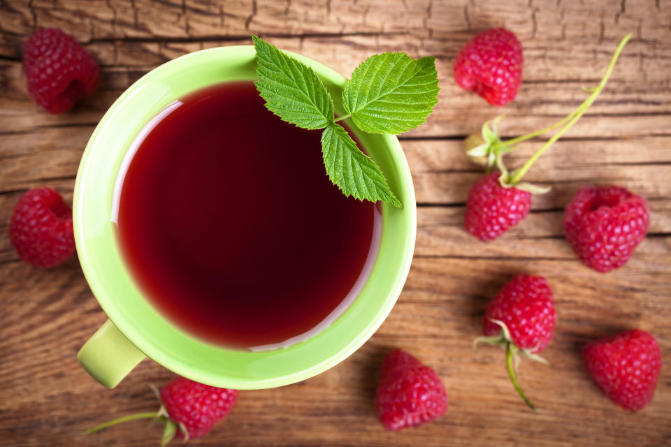 Raspberry tea with berry fruit on wooden table background. Top view. Raspberry tea is said to make birthing easier, with many new moms on social media promising its benefits in the late stage of pregnancy. (Getty)