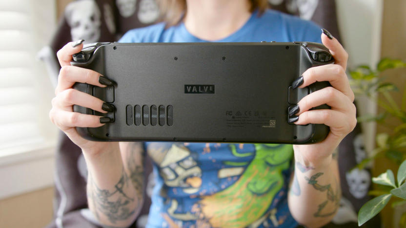 A woman holds up a Steam Deck handheld console with the back of it facing the camera.