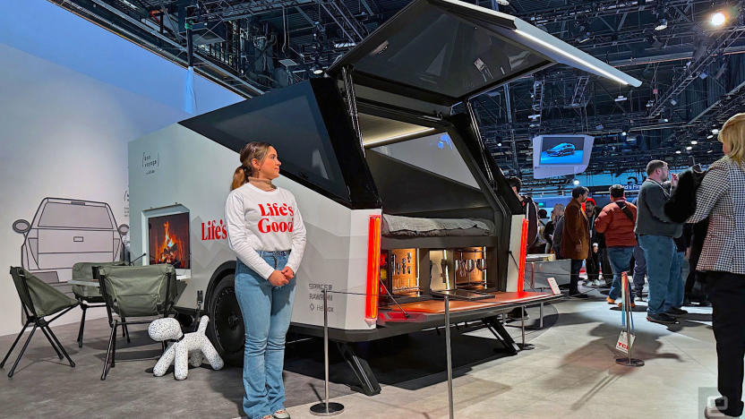 A woman standing next to a high-tech concept trailer from LG at CES 2024. There are camping chairs to the side of the trailer. 