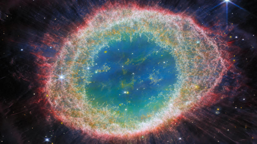 Detailed image of the Ring Nebula, captured by the Webb Telescope. It's an enormous gassy ring with reddish outer rings, which move towards more green and blue near the center.
