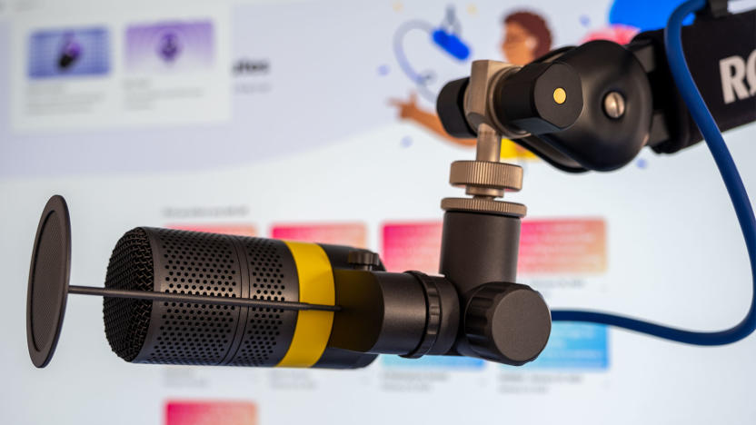 A microphone is pictured infront of a monitor showing Adobe's Podcast tool.
