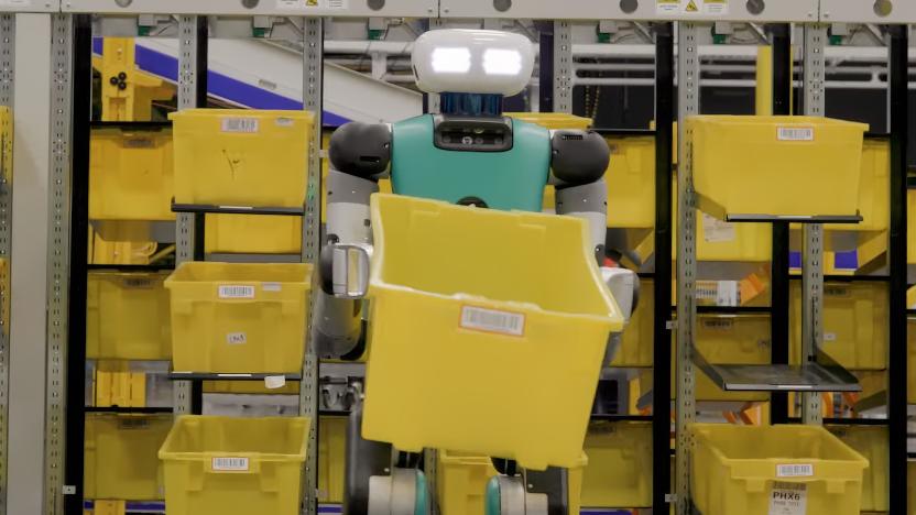 A humanoid robot with glowing eyes standing in a warehouse holding an empty yellow crate.