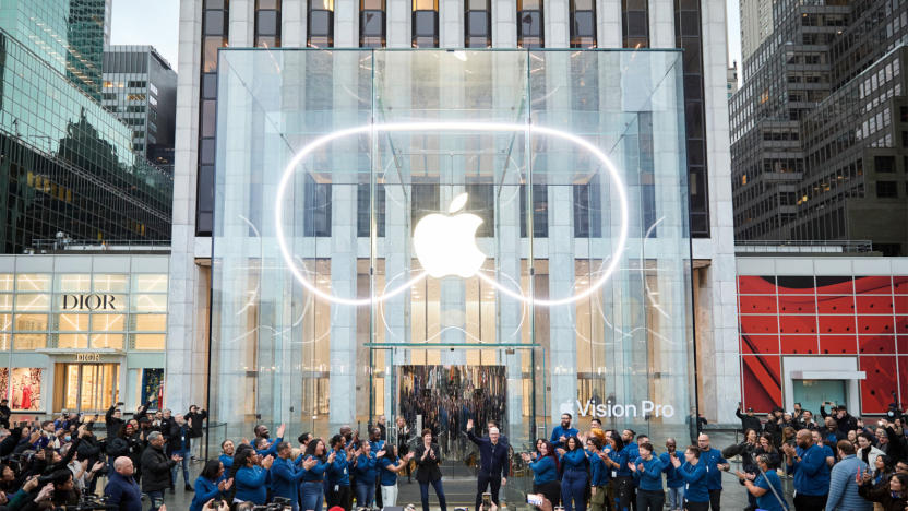 The facade of an Apple Store with the Apple logo lit up and surrounded by the shape of the Vision Pro headset.