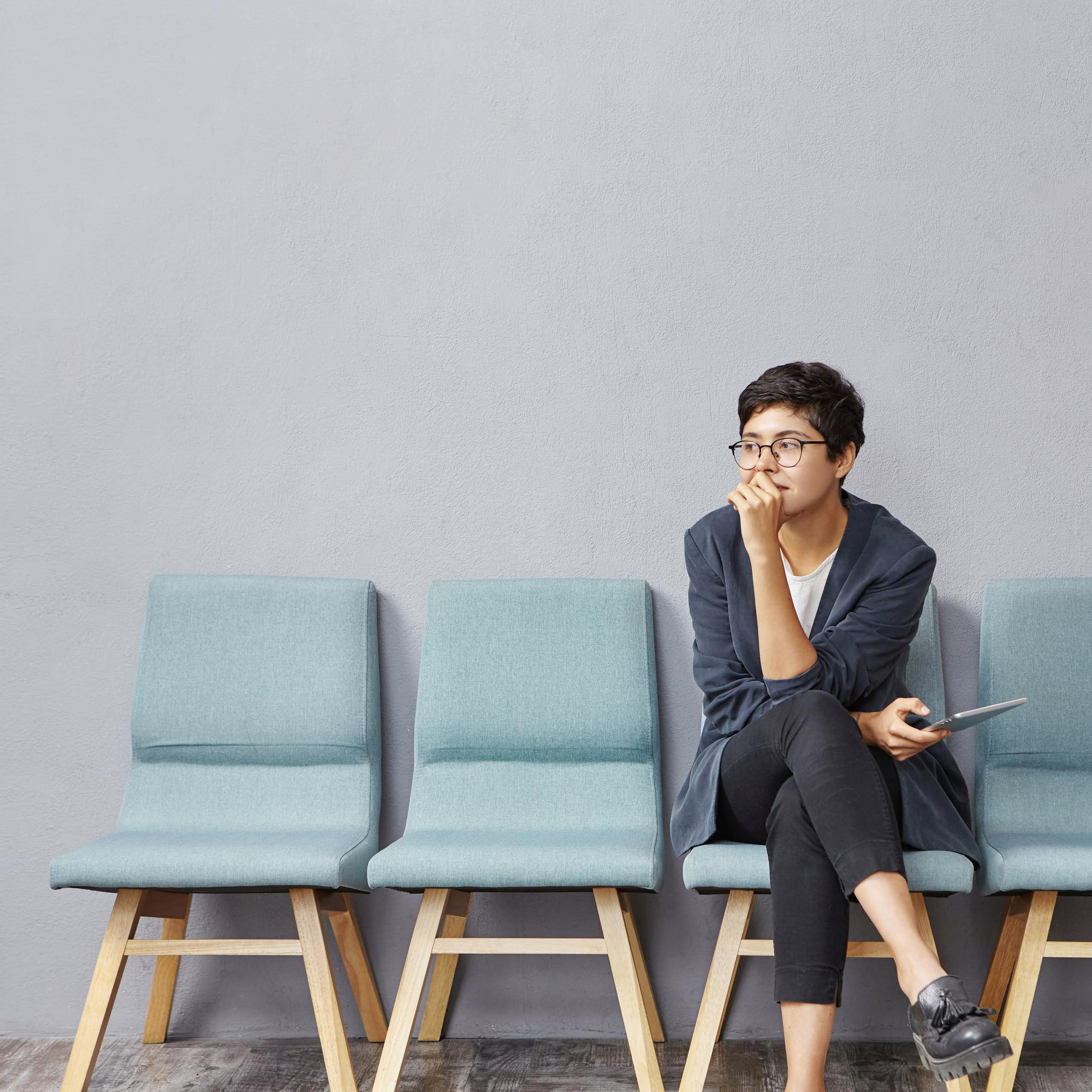 Woman sits on chair in row with her hand resting against her mouth