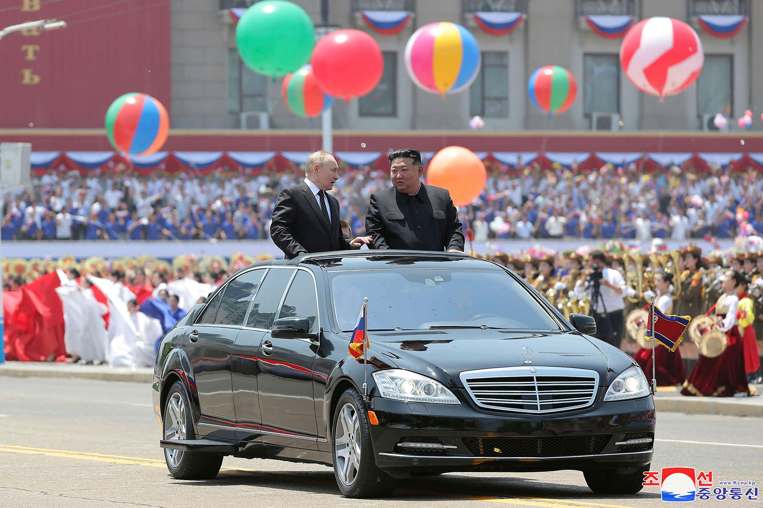 Kim Jung Un and Vladimir Putin in an open top car.