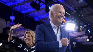 President Joe Biden and first lady Jill Biden walk off stage after speaking at a campaign rally.