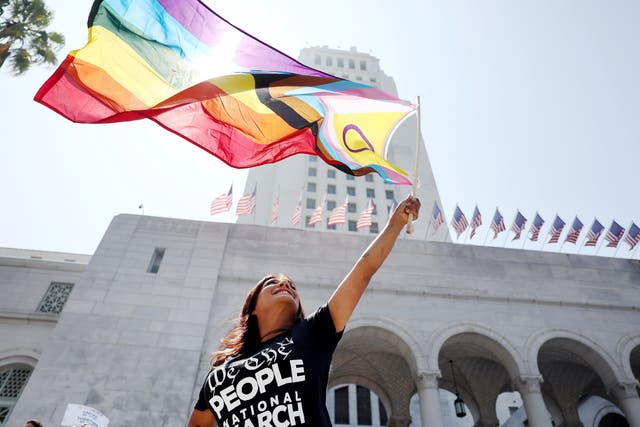 <p>A protester waves a Pride flag incorporating the purple circle emblem of the intersex rights movement outside the Los Angeles city hall in July 2023</p>