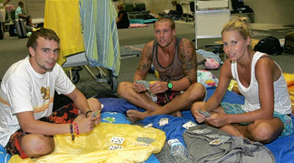 Waiting game: Daniel Greenwell, Russ Camm and his girlfriend Kim Mellor pass the time by playing cards at Bangkok airport