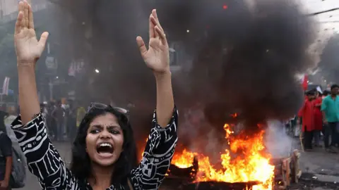 An activist is protesting and burning an effigy and tires as they block a road during a protest against a recent scam in the NEET and UGC-NET exams in Kolkata, India, on June 25, 2024. 